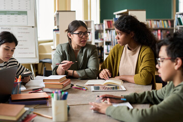 Mentor talking to students at desk in group class setting
