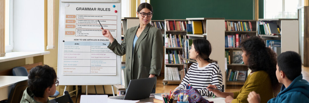 Young mentor explaining grammar rules to students in a classroom setting