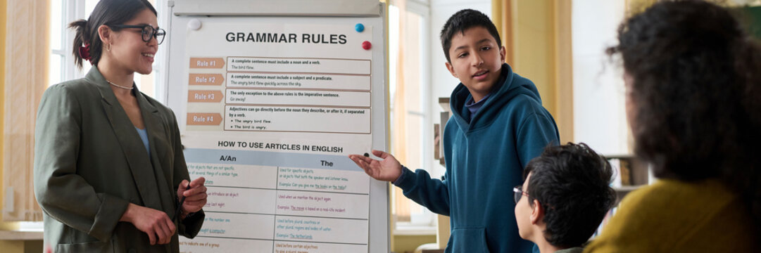 Young woman and children discussing grammar rules in a classroom setting