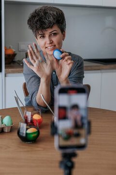 Woman vlogging a tutorial on decorating Easter eggs at home
