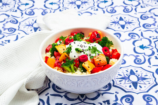 Naklejki Bowl of couscous with grilled vegetables and yoghurt sauce on a patterned tablecloth