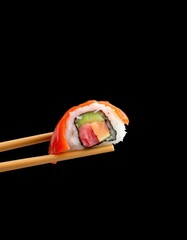 Chopsticks delicately hold a vibrant sushi piece against a stark black backdrop, healthy food, elegant