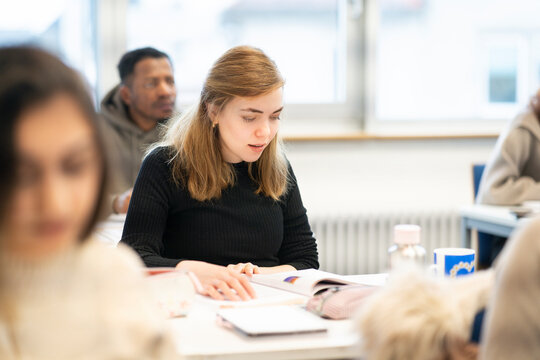 Female student smiling while studying in a multicultural classroom