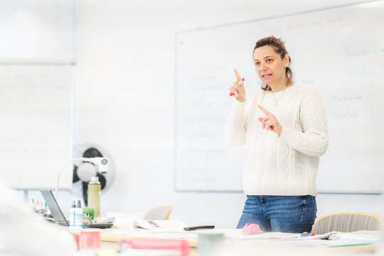 Teacher explaining German rules in a friendly classroom atmosphere during an integration course session.