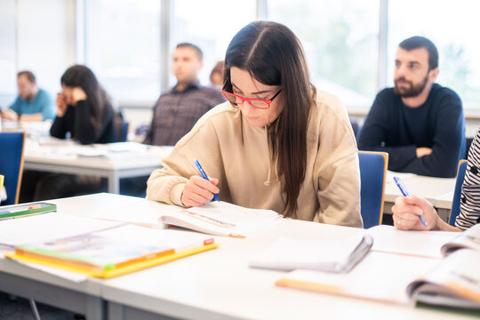 Female student with red glasses studying in a language course classroom