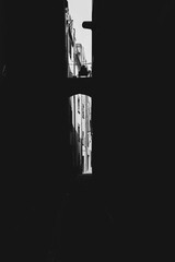 Dark narrow passage between buildings with a sunny street in the end