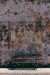 Empty bench next to the old shabby wall