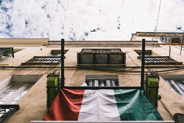 Italian flag on the facade of the building with cloudy blue sky on the background