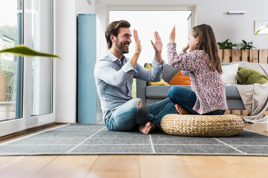 Father and daughter having fun at home giving a high five