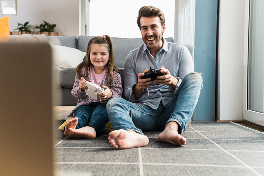 Father and daughter playing video games at home enjoying quality time together
