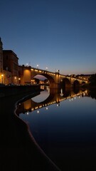 Obraz premium Elbe Twilight in Germany Dresden captured in serene night scene with illuminated stone bridge over calm river. Concept of Elbe Twilight in Germany Dresden showcasing tranquil landscape.