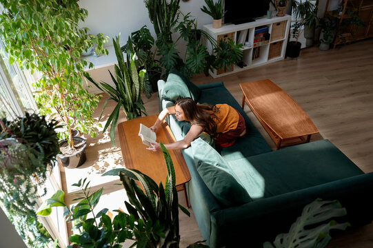 Yung woman reading a book on the couch in the living room