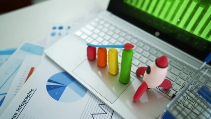 Creative Business Analysis with Clay Graph and Rocket Model, A laptop keyboard with colorful clay bar graph and rocket model, business charts in background - Powered by Adobe