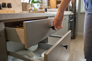 Person opens a kitchen drawer with various utensils in wooden cutlery tray. Woman opening kitchen...