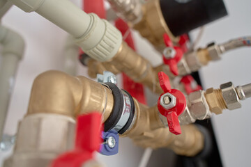 Plumbing system with brass pipes, red valves, and fittings. Heating system in residential building