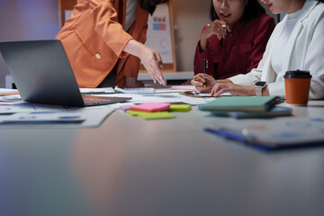 Businesswomen working late analyzing financial reports in office meeting