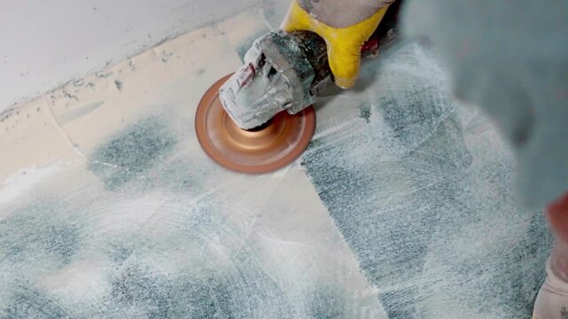 Construction worker polishing epoxy resin floor with sander
