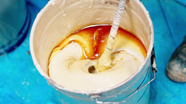Worker mixing epoxy resin and hardener in a bucket