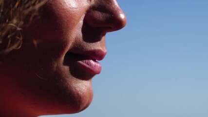 Woman, beach, lipstick - pretty lady applies protective lipstick for lip care. On beach, woman uses nourishing lipstick after day of sun exposure to refresh lips. Close up, Slow motion