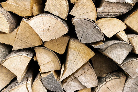 Chopped firewood stacked in a pile. Pile of logs for fireplace. Background of stacked firewood. Woodshed