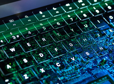 Illuminated laptop keyboard with visible circuit board representing cybersecurity and AI