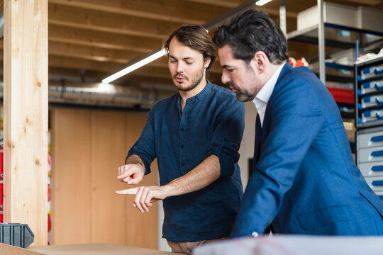 Businessman and employee talking in factory
