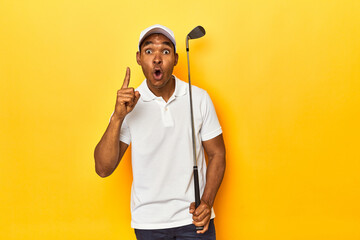 Naklejka premium African American man golfer, yellow studio backdrop, having an idea, inspiration concept.