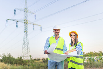 Engineers discussing plans for electricity grid while standing near power lines
