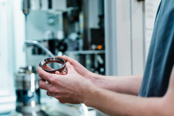 Engineer checking circular machine part while standing at industry