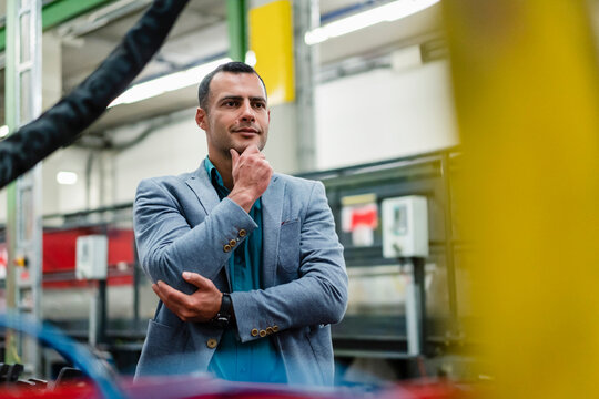 Thoughtful businessman with hand on chin in industry