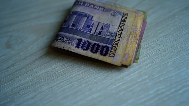 Stack of Bangladeshi Taka Banknotes, A stack of folded Bangladeshi Taka banknotes on a wooden surface