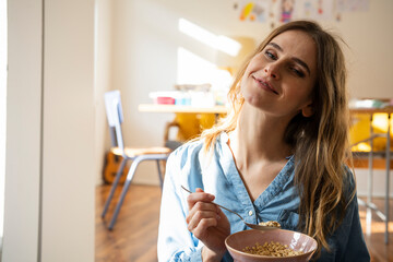 Woman enjoying a healthy breakfast of muesli at home in the morning sunlight