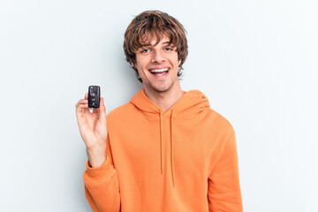 Young caucasian man holding car keys isolated on blue background happy, smiling and cheerful.