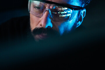 IT specialist analyzing software code reflection in glasses