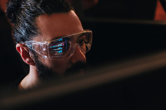 Programmer studying code with reflection in glasses indoors