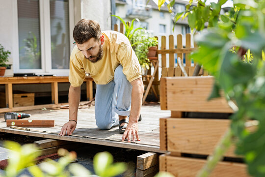 Young handyman building wood terrace in front of his home