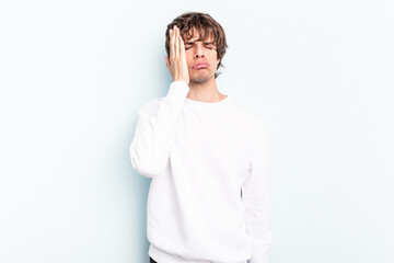 Young caucasian man isolated on blue background tired and very sleepy keeping hand on head.