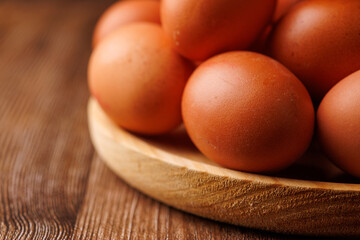 Close-up of brown eggs in a wooden plate on dark wood table, symbolizing inflation