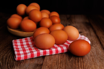 Close-up of brown eggs arranged on a wooden plate over a red and white napkin, highlighting the impact of rising egg prices.