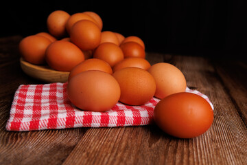 Brown eggs resting on a wooden plate atop a cloth napkin on a dark wooden table, emphasizing rising food costs and market inflation.