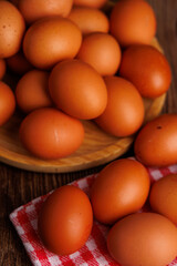Rustic wooden plate with brown eggs placed over a red and white napkin on a wooden surface, highlighting economic inflation.