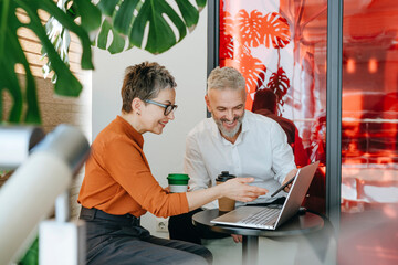 Business colleagues discussing work on a laptop in a modern office