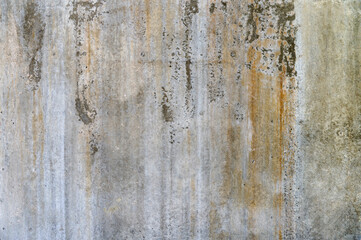 Close-up view of an aged concrete surface showing rust marks and vertical streaks under natural light.