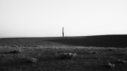 A singular object stands atop a distant barren landscape