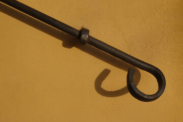 End of handrail with shadow on the yellow wall, fixed to the wall