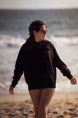 Young woman with and glasses on the shore of the beach in Santa Monica, California wearing sweatshirt.