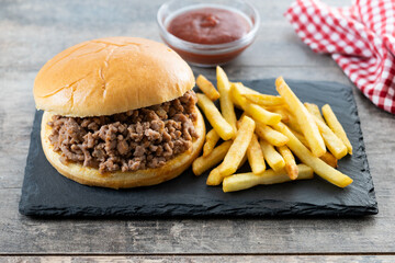 Traditional sloppy joe sandwich with french fries on wooden table
