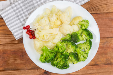 Boiled broccoli and cauliflower on dish on a rustic table