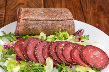 Dry-cured sausage slices against piece of the same sausage
