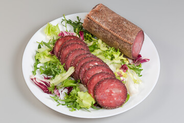 Dry-cured sausage slices and piece of the same sausage
